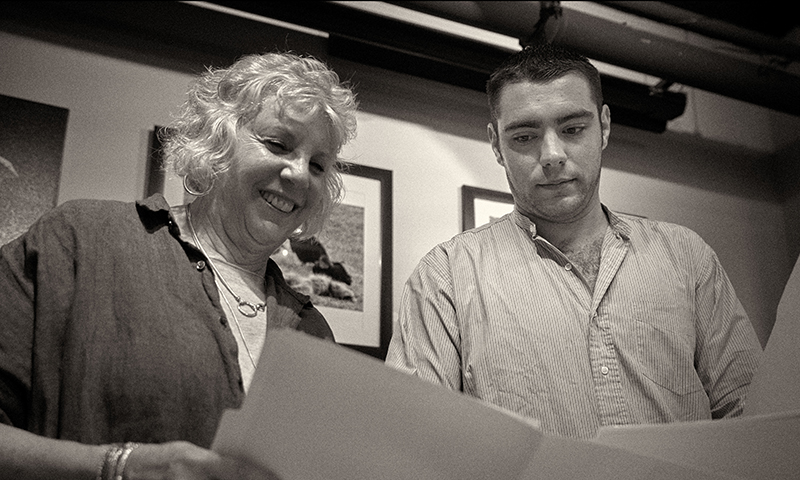 Black and white photos of a Caucasian female and male overlooking a document.