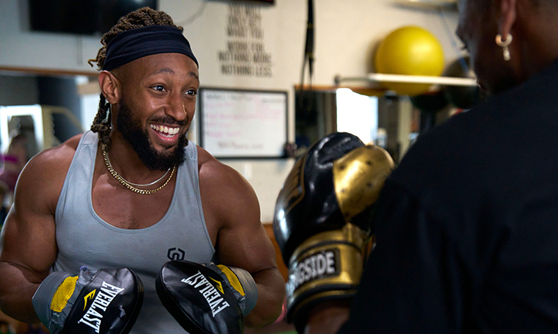 African American male wearing boxing gloves and sparring with another trainer